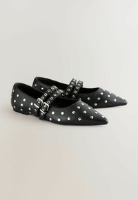 Scarpe nere eleganti con punta affusolata, decorate con pois bianchi, con doppie fibbie e borchie in tonalità argentata. Realizzate in pelle liscia.