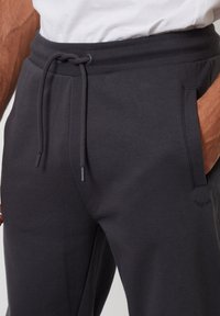 Mörkgrå mjukisbyxor i mjukt tyg med justerbar dragsko i midjan, sidfickor och subtil logodetalj.