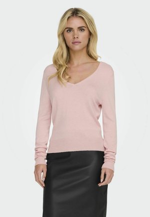 Helles rosa V-Ausschnitt-Pullover mit langen Ärmeln, aus weichem, strukturiertem Stoff; kombiniert mit einem eleganten schwarzen Rock.