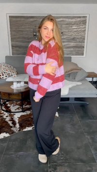 Striped cardigan i rødt og lavendel, teksturert stoff, cropped design. Sorte vide bukser og beige fottøy. Myk, koselig innendørs setting.