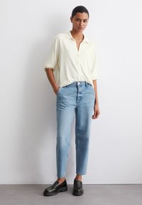 Lys gul knapp-up skjorte med korte ermer, kombinert med lys blå, litt slitte rette jeans og svarte loafers.