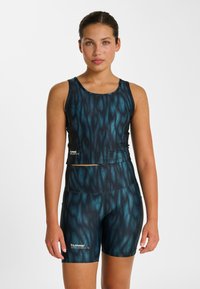 Ensemble crop top de sport et short bleu foncé avec un motif fluide et ondulé. Tissu léger et extensible, avec un logo en bas à gauche.