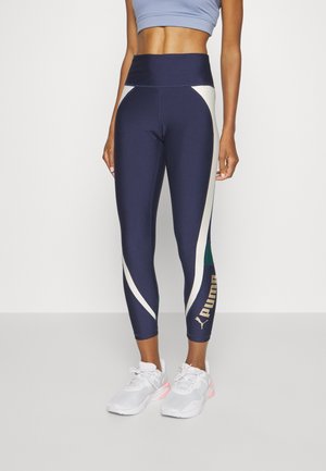 Marineblå leggings med cremede og grønne accenter, høj talje, med et logo i guld. Lavet af strækbart, letvægtsstof.