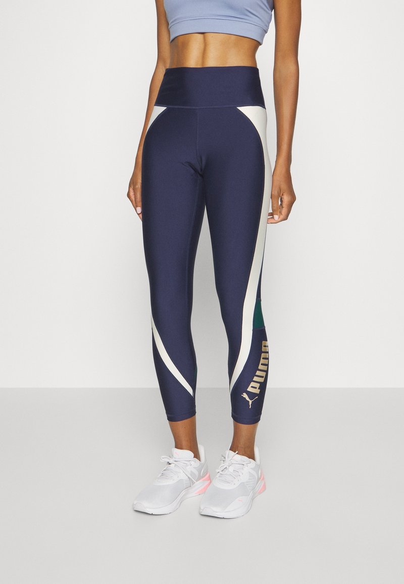 Leggings blu navy con accenti crema e verde, vita alta, con dettaglio logo in oro. Realizzati in un tessuto elastico e leggero.