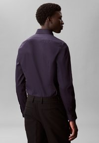 Navy button-up shirt with a standard collar, long sleeves, and a smooth texture, paired with black pants featuring an elastic waistband.