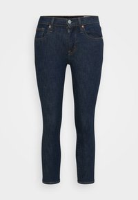 Jeans en denim bleu foncé avec une coupe ajustée, dotés d'une braguette zippée, d'une fermeture à bouton et de poches avant. Texture lisse avec des détails de couture subtils.