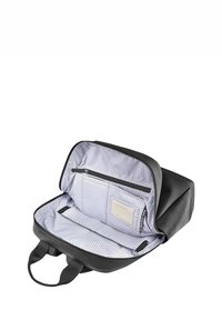 Borsa in materiale sintetico nero con un ampio interno, foderata con motivo a pois, tasca con zip e portanome. Dotata di manici robusti.