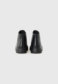 Schwarze High-Top-Sneaker aus glattem Leder mit einer strukturierten Gummisohle und einem Logodetail auf der Rückseite. Elegantes, minimalistisches Design.