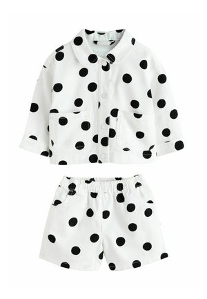 Weißes Baumwoll-Outfit mit einem Jackett mit Kragen und passenden Shorts, beide mit schwarzen Tupfen und Fronttaschen, elastischem Bund.