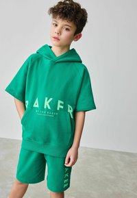 Vihreä lyhythihainen huppari ja yhteensopivat shortsit, joissa on suuri valkoinen "BAKER" -teksti. Korkealaatuinen kangas, rento istuvuus ja etutasku.
