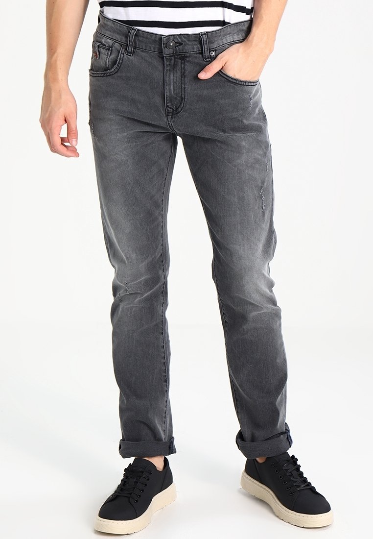 Tmavě šedé džíny s mírným opotřebením, slim fit a jemným voskováním. V kombinaci s černými šněrovacími teniskami a pruhovaným tričkem.