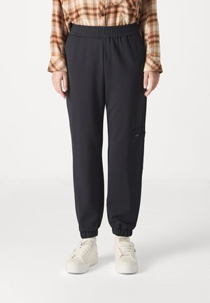 Sorte joggebukser med elastisk midje og oppbrettede ankler. Har en sidelomme, laget av mykt stoff med en glatt tekstur.