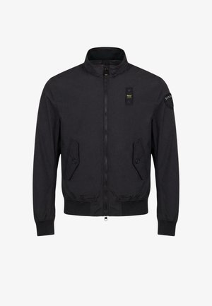 Zwarte bomberjack met ritssluiting, opstaande kraag, twee voorzakken met knopen en klep, geribde manchetten en zoom, en merkpatches op borst en mouw.