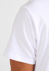 White cotton T-shirt featuring a crew neck and short sleeves. Soft texture with a smooth finish and no visible patterns.