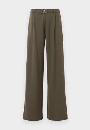 Wijde broek in donker olijfgroene stof met een ceintuur en een gouden ronde gesp, en plooien aan de voorkant voor extra detail.