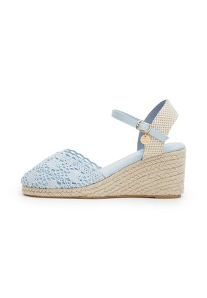 Sandalo con zeppa azzurro chiaro con parte frontale intrecciata, tacco platform beige intrecciato e cinturino alla caviglia regolabile con fibbia dorata e ciondolo.