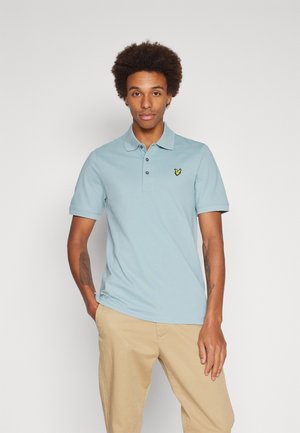 Polo de color azul claro hecho de algodón, con tapeta de tres botones y mangas cortas. Presenta un pequeño logo amarillo en el pecho.