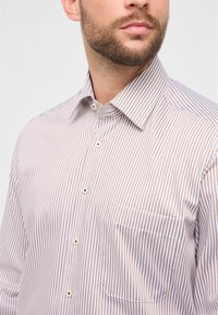 Gestreept overhemd in lichtbeige en bruin, gemaakt van gladde stof. Voorzien van een button-down kraag, een voorzak en een knoopsluiting.