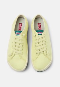 Limgröna kanvas sneakers med rund tå, snörningsdesign, vadderad krage och kontrasterande logotypetikett på tungan. Texturerad gummisula.