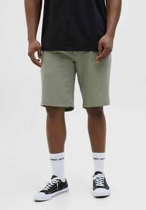 Pantaloni corti khaki con taglio dritto, in cotone, orlo arrotolato, abbinati a sneaker nere e calzini bianchi. Design semplice e stile casual.