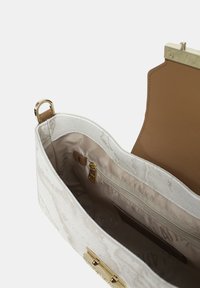 Borsa bianca con un esterno texture, accessori in oro e un interno beige che presenta una tasca con zip e una fodera stampata con il logo del brand.