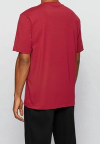 Bordová bavlněná tričko s krátkým rukávem, kulatým výstřihem a volným střihem. Hladký povrch bez viditelných vzorů nebo akcentů.