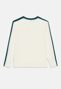 Långärmad skjorta i off-white bomull med mörkgröna axelstrimmor. Crew neck-design med avslappnad passform och sydd detaljer.