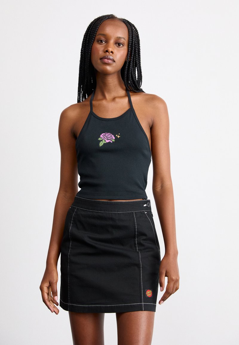 Top nero con scollo all'americana e ricamo di una rosa viola, abbinato a una gonna di jeans nera con cuciture bianche e una patch logo rossa.