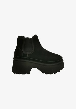 Stivali alla caviglia in suede nero con pannelli laterali elasticizzati, suola in gomma robusta e texture liscia. Presentano una punta arrotondata e una cucitura minimale.