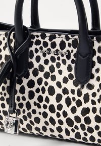 Crno-bijela torba s uzorkom leoparda s crnim kožnim ručkama i srebrnim logotipom. Ima srebrni akcent s katancem. Strukturalni dizajn.