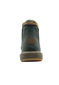 Bota de lona verde con suela de goma marrón y forro de cuadros. Presenta una superficie texturizada y un parche de logo circular en el talón.