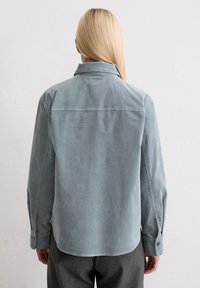 Lichtblauw corduroy overhemd met een spitse kraag, lange mouwen en knoopmanchetten. Gladde textuur met een licht getailleerde pasvorm en een afgeronde zoom.