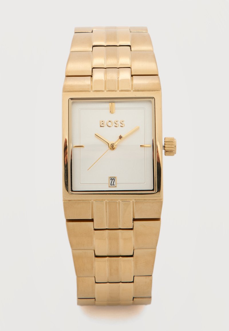 Ρολόι χειρός ορθογώνιου σχήματος με χρυσό τόνο, λευκό καντράν, χρυσά δείκτες, παράθυρο ημερομηνίας στις 6 η ώρα και ενωμένο μεταλλικό λουρί.