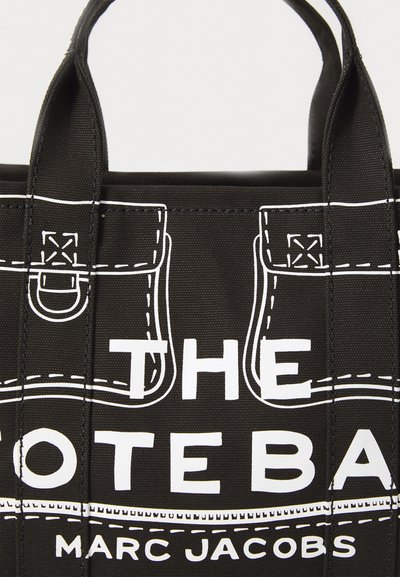 Melna tote soma ar baltu izdrukātu dizainu, kas atgādina kabatas. Tās iezīme ir cietas rokas un uzraksts, kas skaidri izteikts – "TOTE BAG" un "MARC JACOBS."