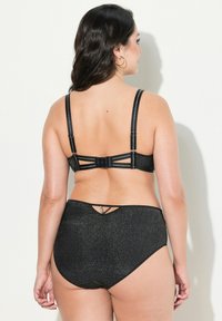 Musta alusvaatesetti, jossa on teksturoitu, kiiltävä materiaali. Rintaliivissä on säädettävät hihnat ja takaklipsi, kun taas korkeavyötäröisissä alushousuissa on pieni aukko-tyyppinen yksityiskohta.