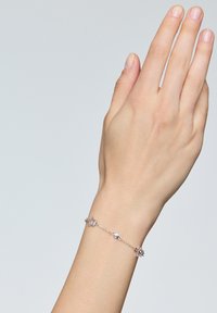 Srebrna bransoletka w kształcie gwiazdy, wykonana z metalowych ogniw, z wieloma gwiazdami o różnych rozmiarach połączonymi delikatnym łańcuszkiem.