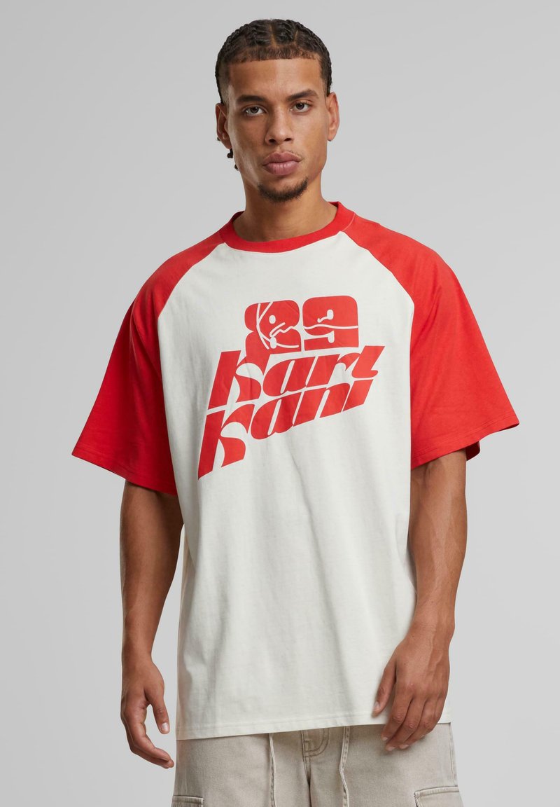 Red and white oversized t-shirt with a graphic print. Short raglan sleeves, soft fabric, and a relaxed fit. Bold logo in red on the front.