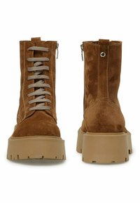 Brune ruskindsankelstøvler med snørebånd foran, grå snørebånd, lynlås og chunky beige plateau såler med tekstureret slidbane.