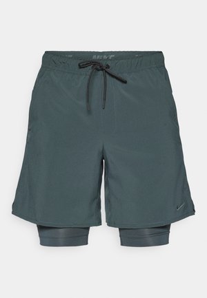 Bermudas deportivas de color gris oscuro con cintura elástica y cordón ajustable. Incluyen pantalones cortos interiores de compresión con un acabado texturizado.