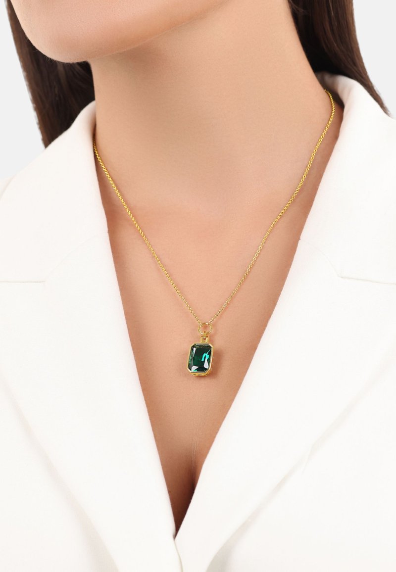 Collana in oro con un pendente rettangolare verde smeraldo dalle estremità sfaccettate, incastonato in un telaio in metallo dorato.