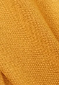 Textilstoff in einem lebhaften Goldgelbton, mit einer glatten, fein gestrickten Textur, die subtile Tiefe und ein einheitliches Muster aufweist.