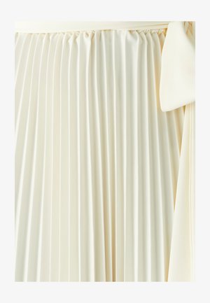 Jupe plissée en tissu crème avec une texture douce ; elle présente une taille élastique et un détail à nouer sur un côté.