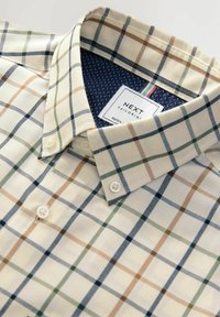 Camisa de cuadros de algodón en crema, con cuadros verdes, azules y marrones. Cuello abotonado con un interior de lunares en navy y etiqueta de la marca.