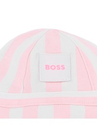 Ριγωτό καπέλο σε ροζ και λευκό βαμβάκι με τετράγωνη ετικέτα που  φέρει τη λέξη "BOSS" σε ροζ. Διαθέτει καμπυλωτό γείσο και δομημένη κορυφή.