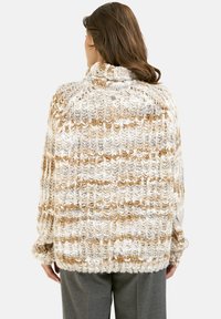 Cremfarbener und beige gestreifter oversized Strickpullover mit hohem Kragen und strukturiertem Garn, der eine lockere Passform und überschnittene Schultern aufweist.
