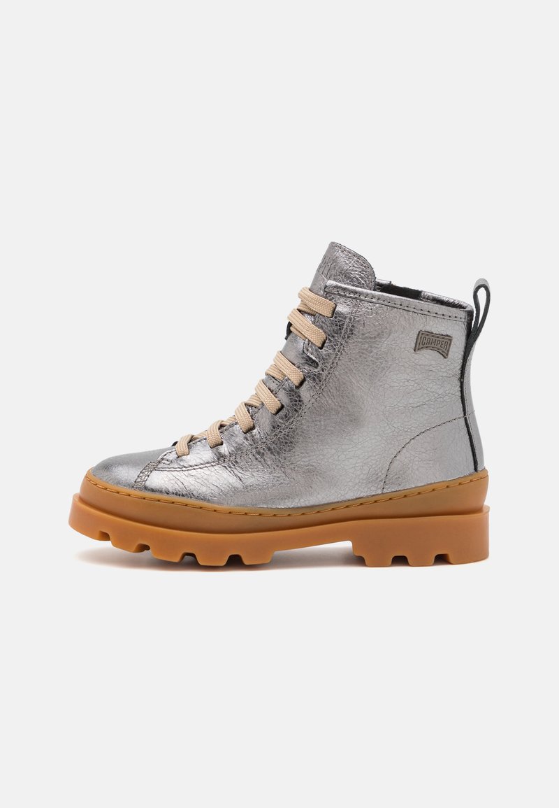 Stivaletto metallico argento con lacci beige, pelle textured, suola in gomma e un accento nero sul retro. Presenta un motivo di battistrada prominente.