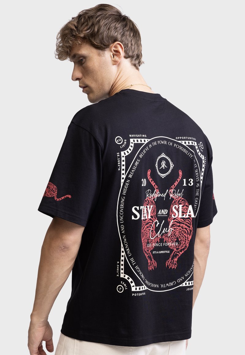 Camiseta de algodón negra con diseño gráfico rojo que presenta un tigre y texto en la parte posterior. Corte relajado y escote clásico.
