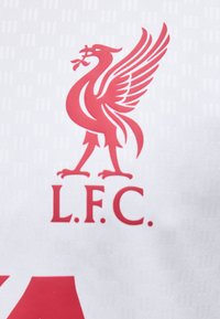 Έμβλημα κόκκινου Liver bird με κείμενο "L.F.C." από κάτω σε λευκό υφασμάτινο φόντο με υφή.