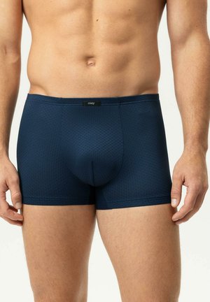Mann trägt dunkelblaue, eng anliegende Boxershorts mit einem dezenten strukturierten Muster und einem kleinen, zentrierten Markenlabel am Bund.