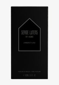 Scatola rettangolare nera con finitura opaca. Presenta un logo pentagonale. Testo in bianco e grigio in grassetto, che recita "SERGE LUTENS AT HOME" e "L'armoire à linge."